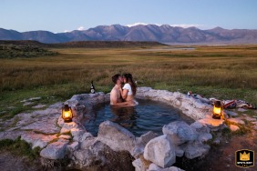 Mammoth Lakes, California, is where a newly married couple relaxes in a natural hot spring, taking a moment to themselves as the sun sets over the distant peaks.